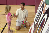 Pre-school student receiving tennis ball to throw
